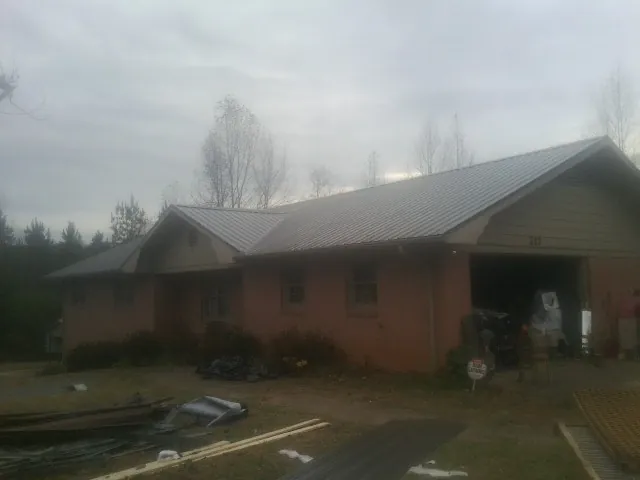 Gray metal roof on a stucco house with an attached garage in Montpelier