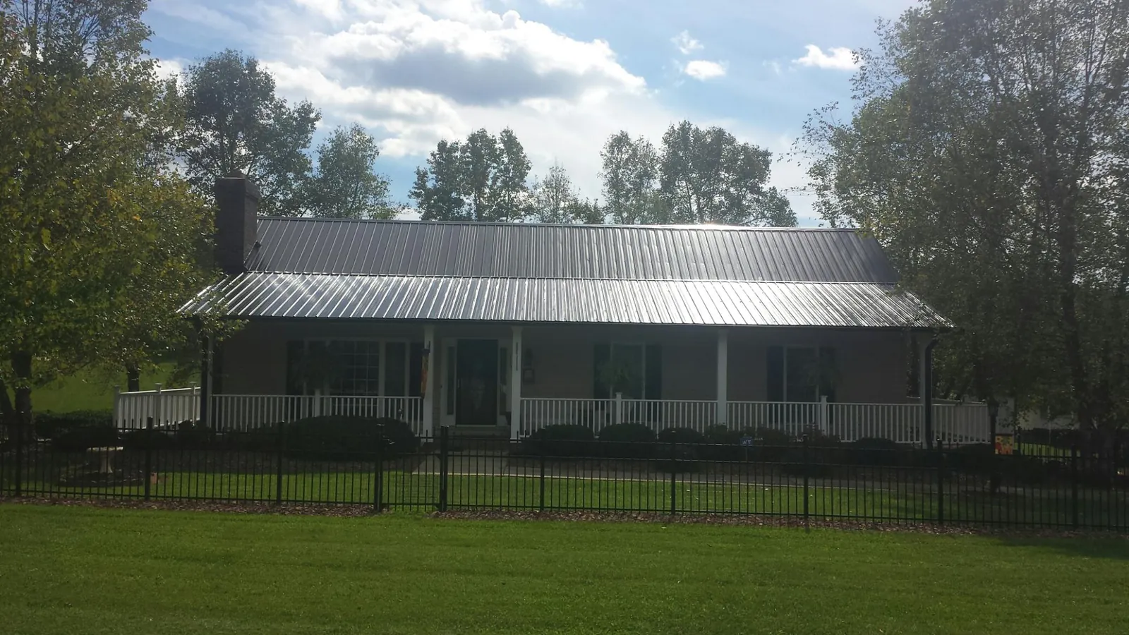 Gray metal roof on a brick ranch with a full width front porch — Gutter Guard Installation work by our crew in Montpelier